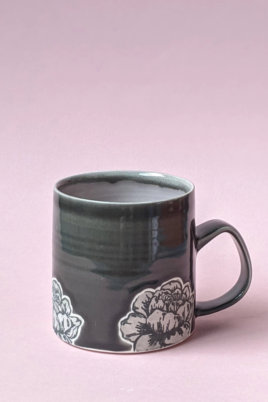 Green mug with floral design on a pink background ©City In Bloom Ceramics