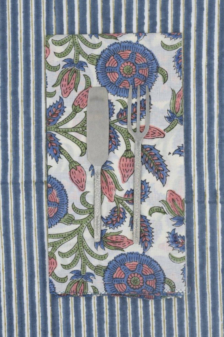 Photo of a utensils on a floral napkin on a blue striped background ©Suzette a Table