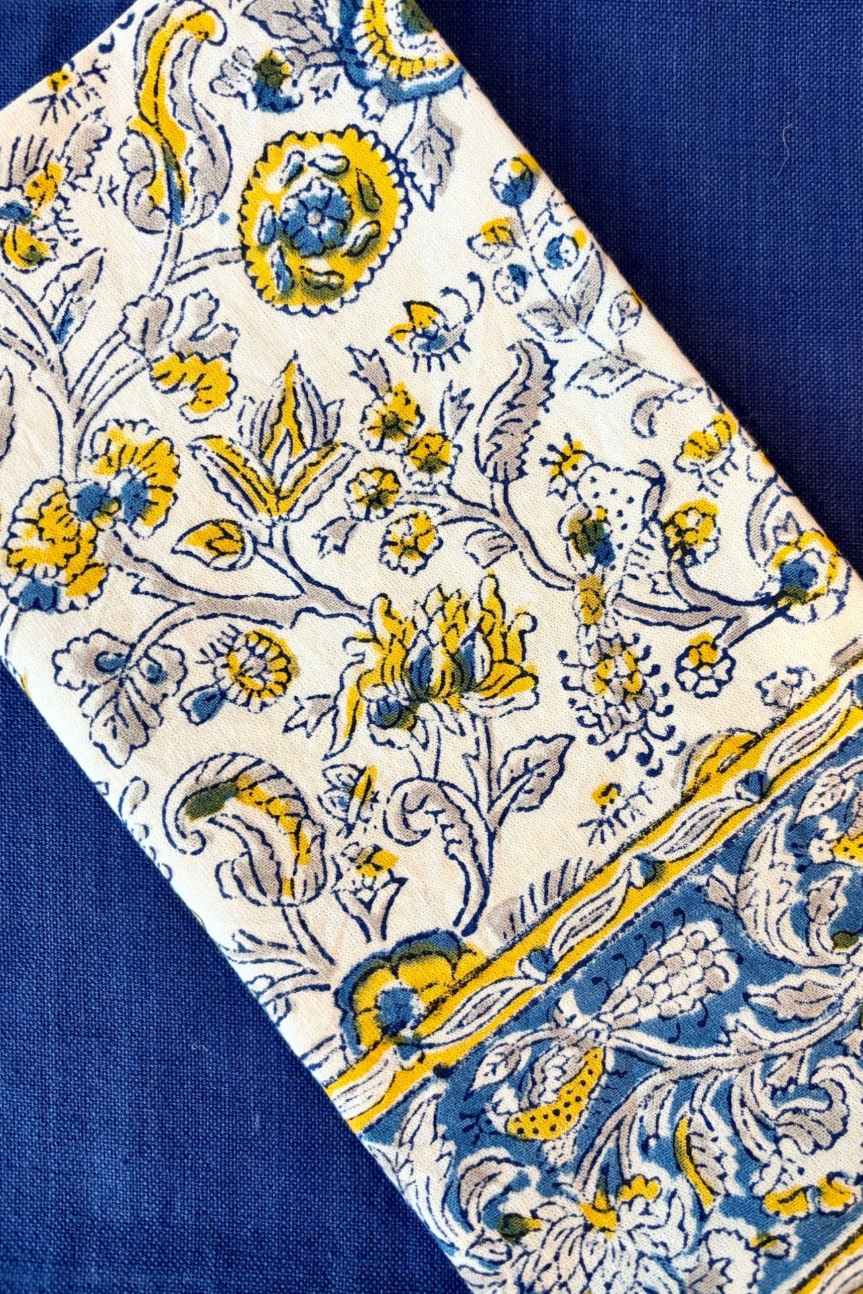 Hand printed, 100% cotton, Provence napkin with yellow and blue floral pattern styled with royal blue napkin ©Sprout Home