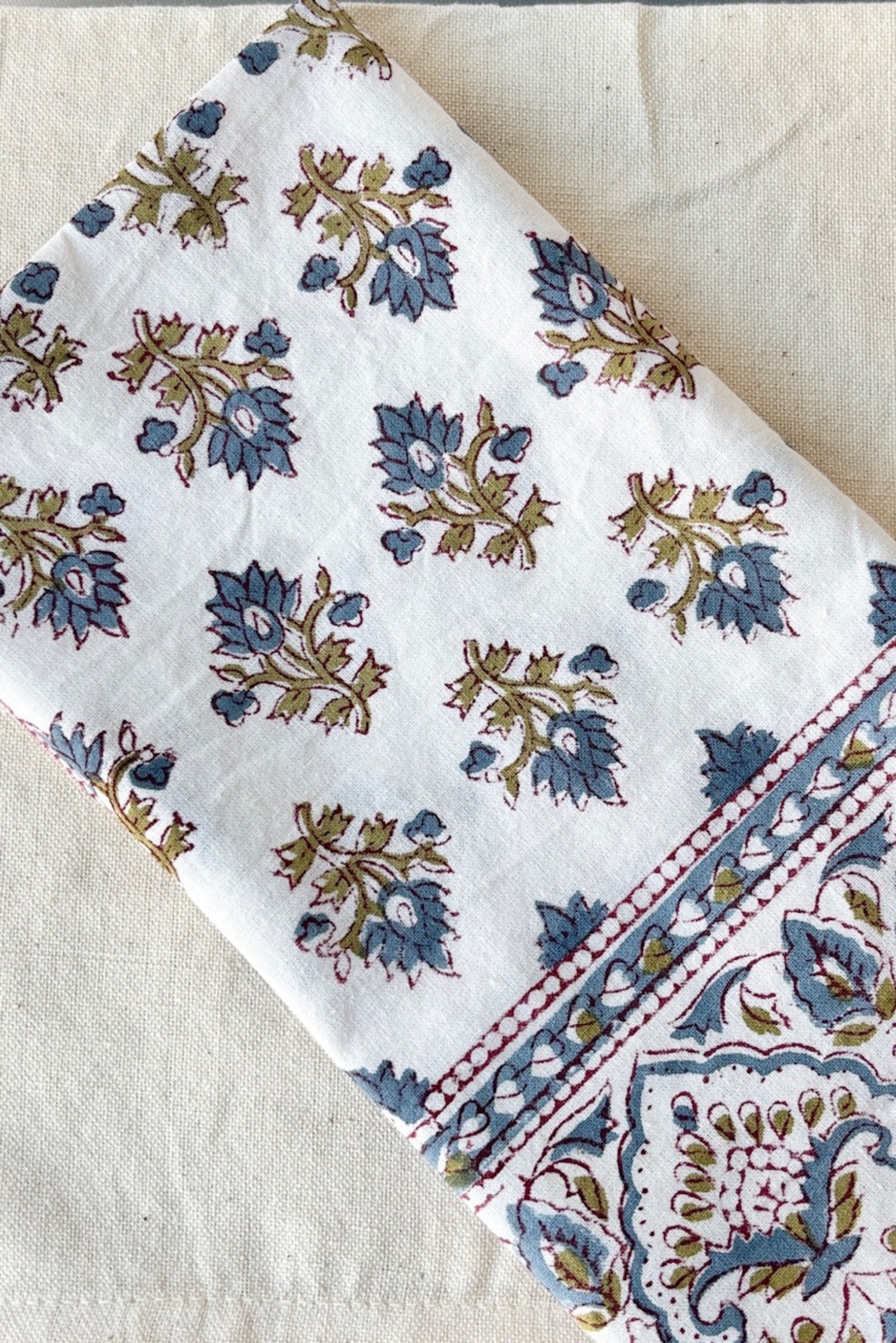Hand printed Silvia napkin with blue and green filagree floral design on a white background ©Sprout Home