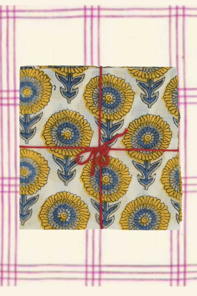 A blue and yellow floral napkin tied with string on a white and pink background ©Suzette a Table