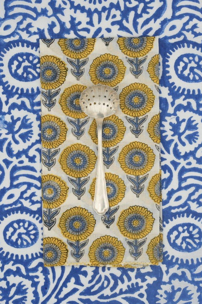 A spoon on a blue and yellow floral napkin on a blue and white background ©Suzette a Table
