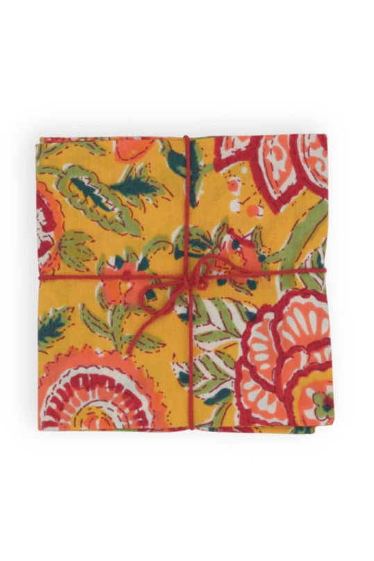Square folded napkins with a colorful floral pattern tied with string on a white background ©Suzette a Table