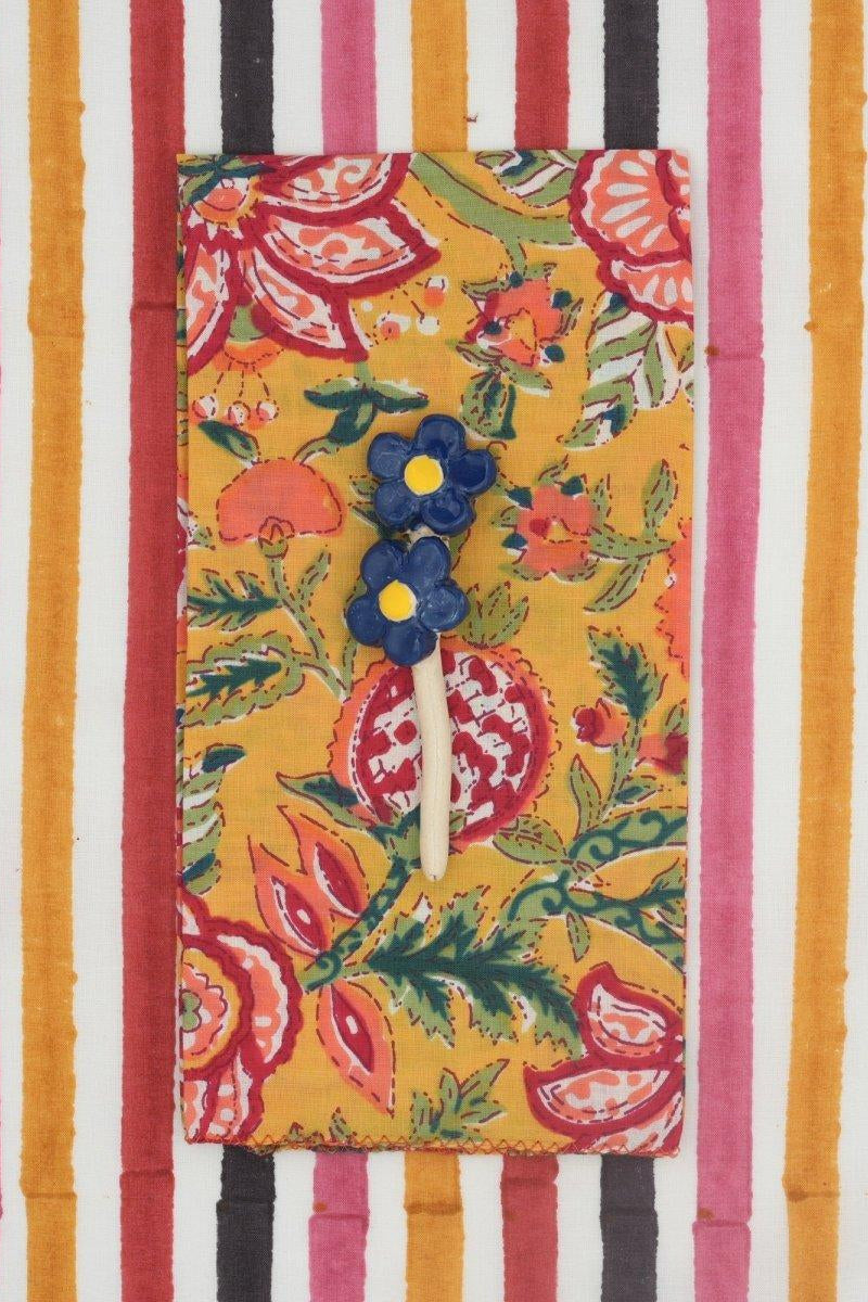A colorful floral napkin on a bright striped background ©Suzette a Table
