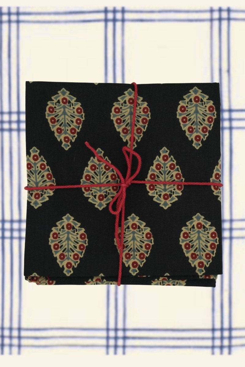 A set of black napkins with a floral pattern against a broad plaid background ©Sprout Home