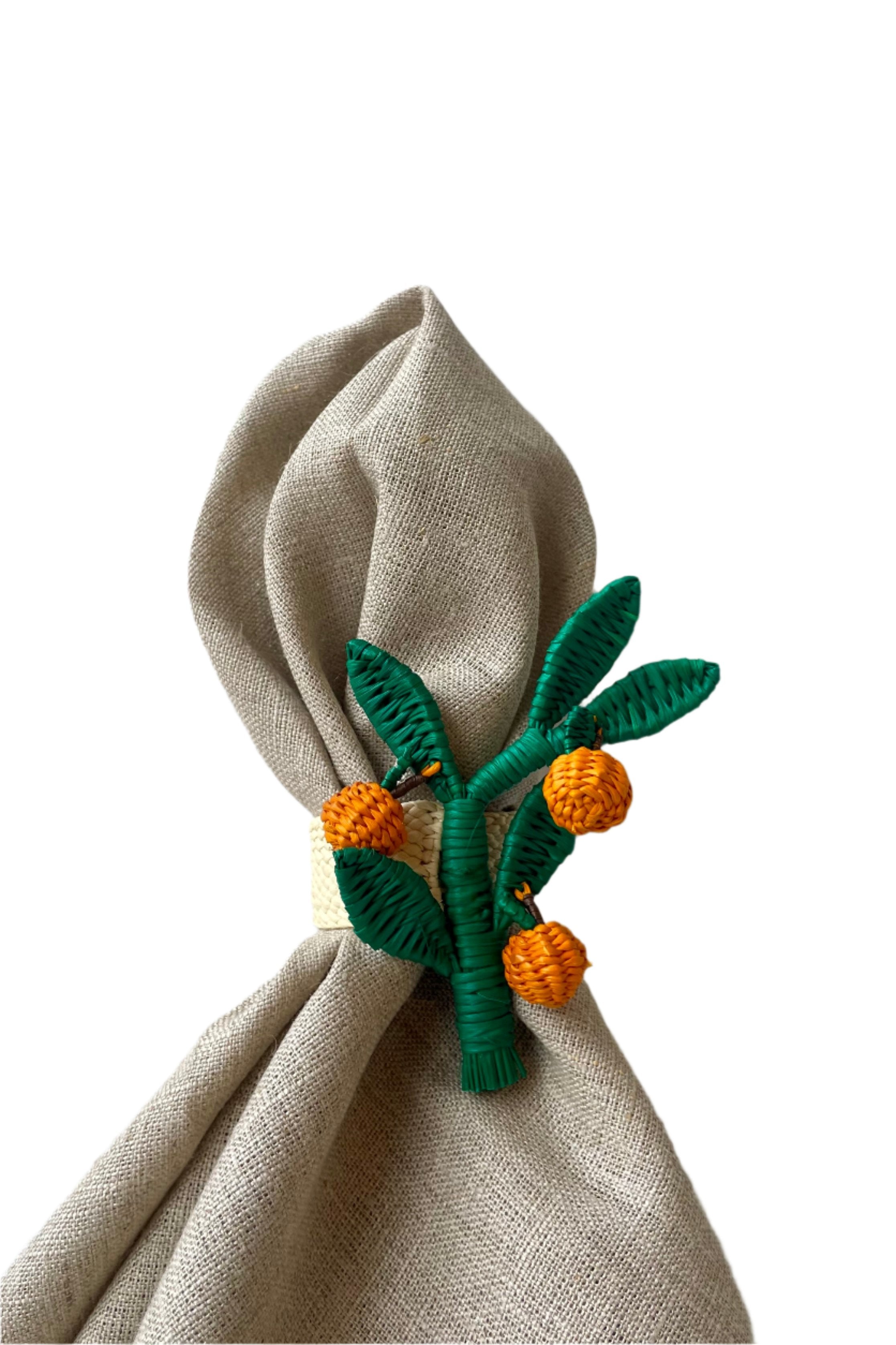 Photo of an Orange Branch Napkin Ring on a neutral napkin. The green and orange palm fiber is wrapped around wire. It is shown in front of a white background.