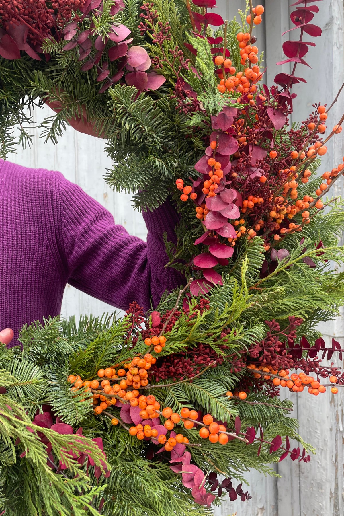 An evergreen wreath with warm color berries and leaves ©Sprout Home
