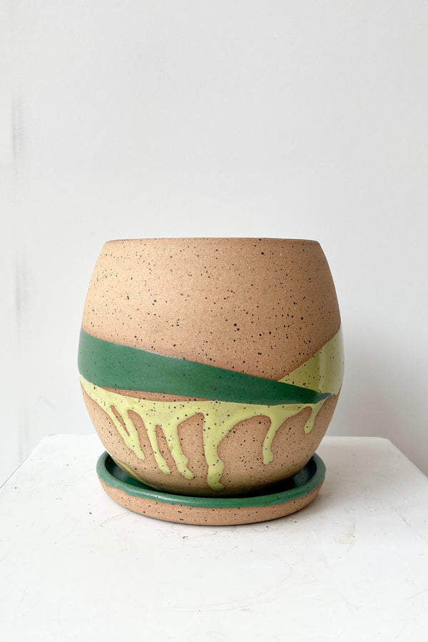 A green splash glazed Orb pot viewed from the side showing the two different green splashes against the neutral base.