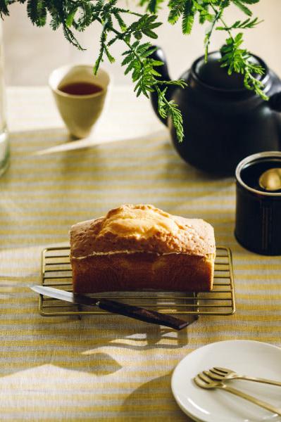 Brass rectangular wire rack by Fog Linen Work with a loaf of bread and knife on top on a table setting. 