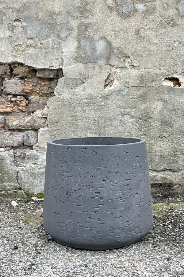 Photo of extra extra large Patt Pot planter with textured matte black finish against a cement wall.