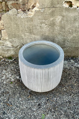 Photo from above of white and gray striped Harith pot against a cement wall.