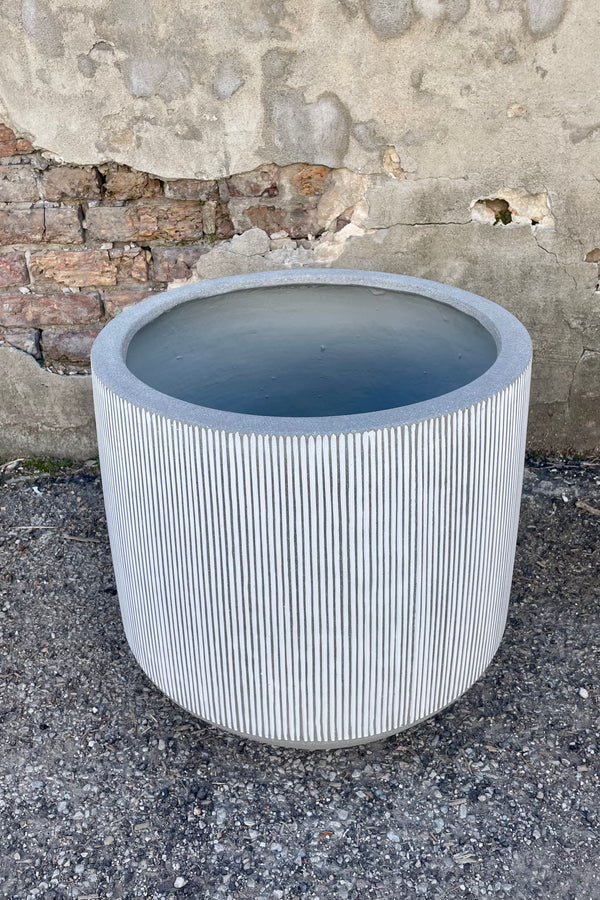 Photo from above of white and gray striped Harith pot against a cement wall.