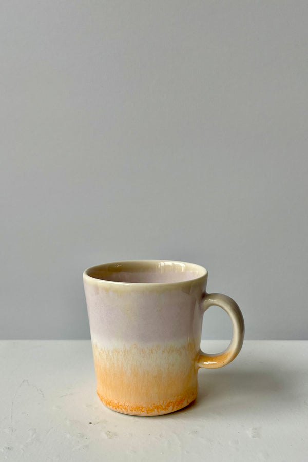 Photo of lavender and peach glazed espresso cup by SGW Lab against a white wall.