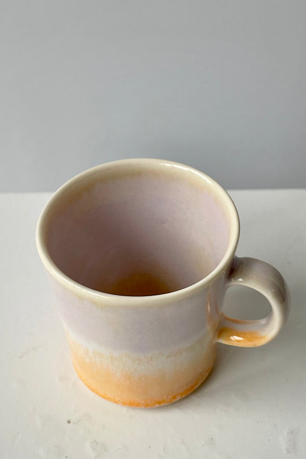 Photo from above of lavender and peach glazed espresso cup by SGW Lab against a white wall.