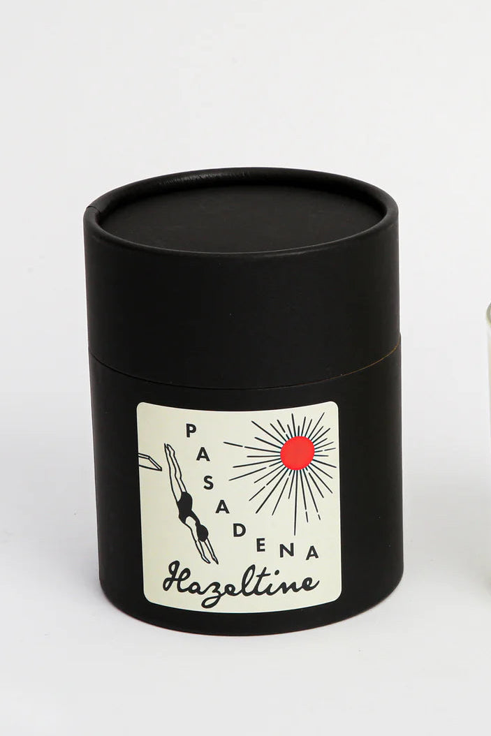 Candle and black cylindrical container with 'Pasadena Hazeltine' label on a white background ©Hazeltine
