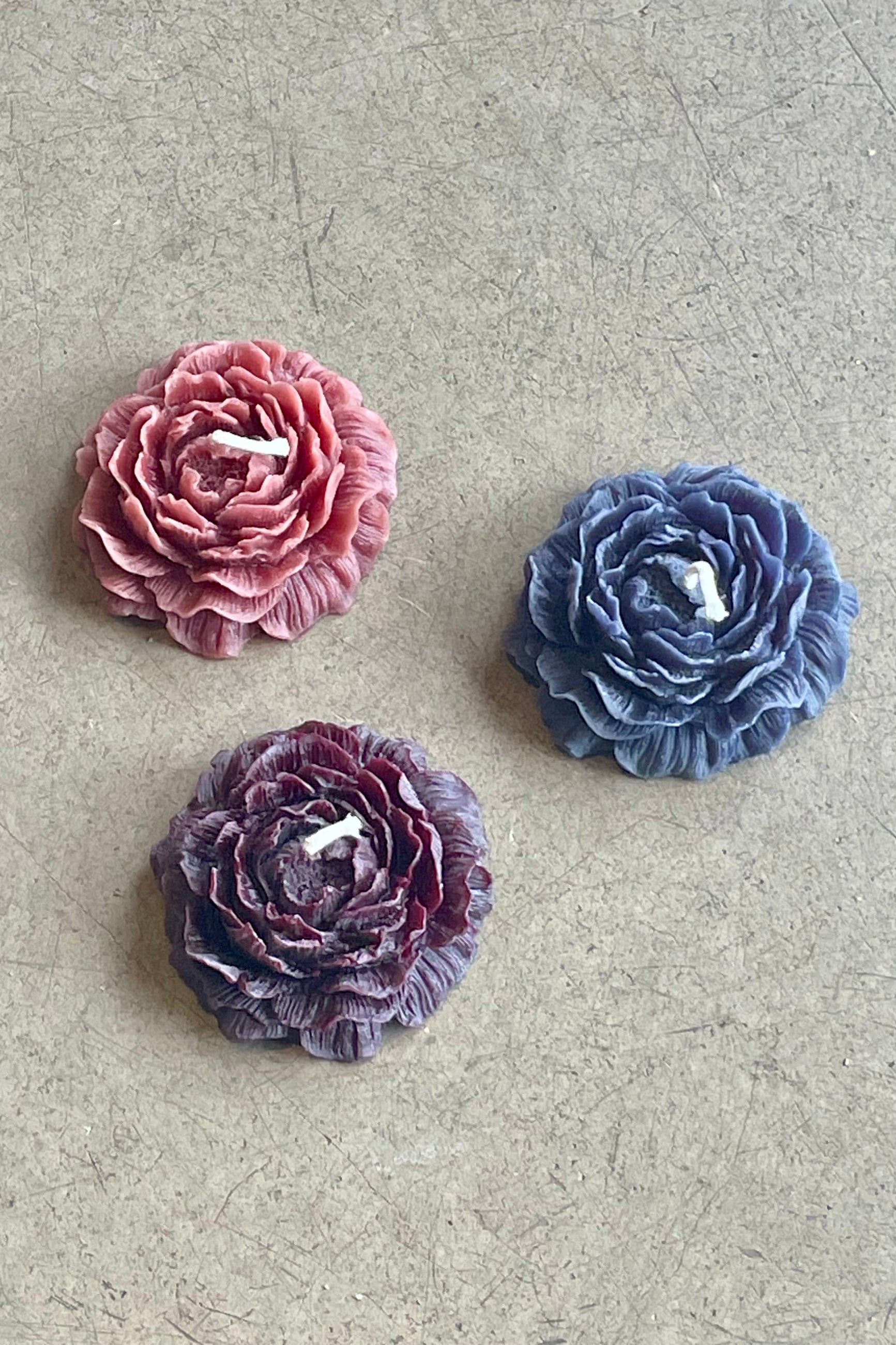 A trio of flower shaped candles in shades of blue and purple ©Sprout Home