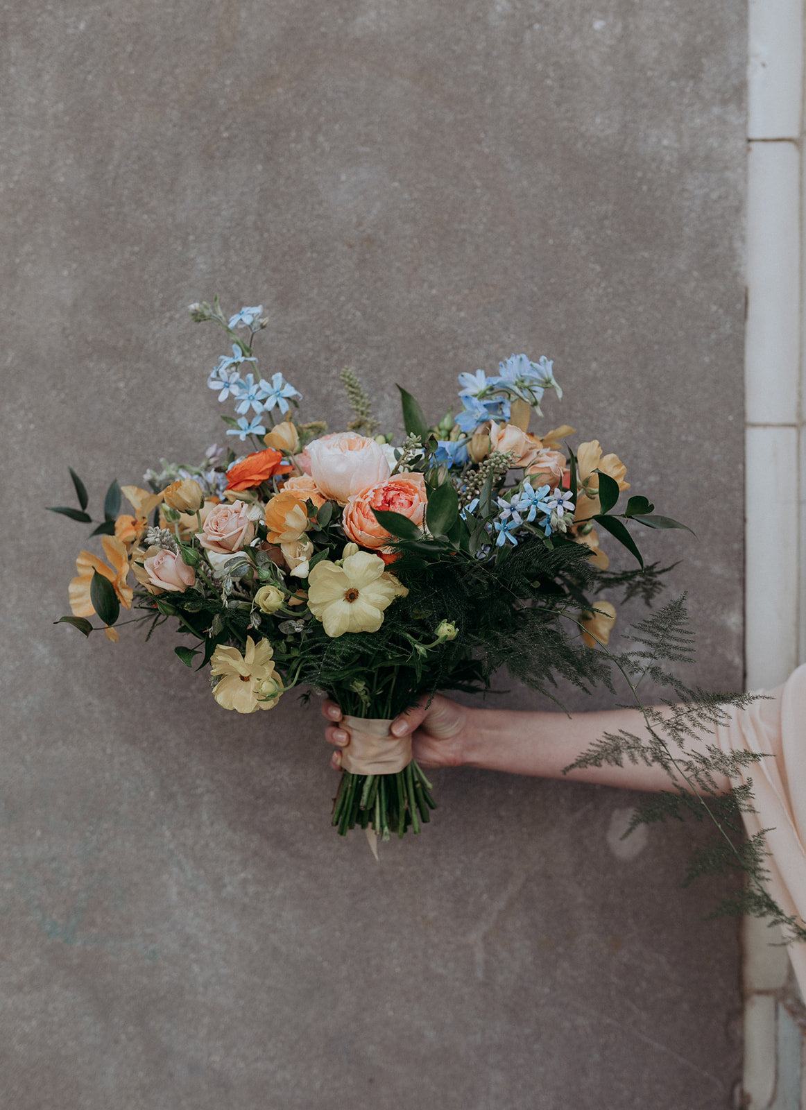 Perish wedding with floral designed by SPROUT HOME. Bridal bouquet in pastel colors, playful and natural with some fluff. Blue flowers on top of creams, yellows and coral.  Photograph by Alisha Toya