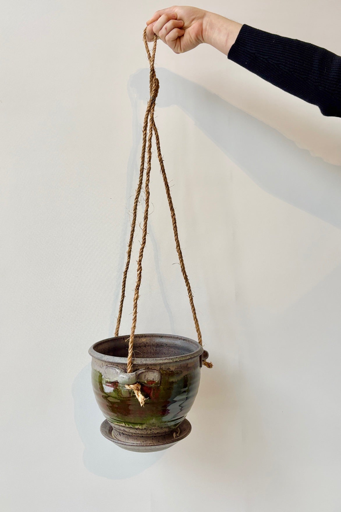 Bruning Pottery 6" diameter Hanging Planter moss & lilac glaze in various shades of green, blue, red and green held in front of white wall ©Sprout Home