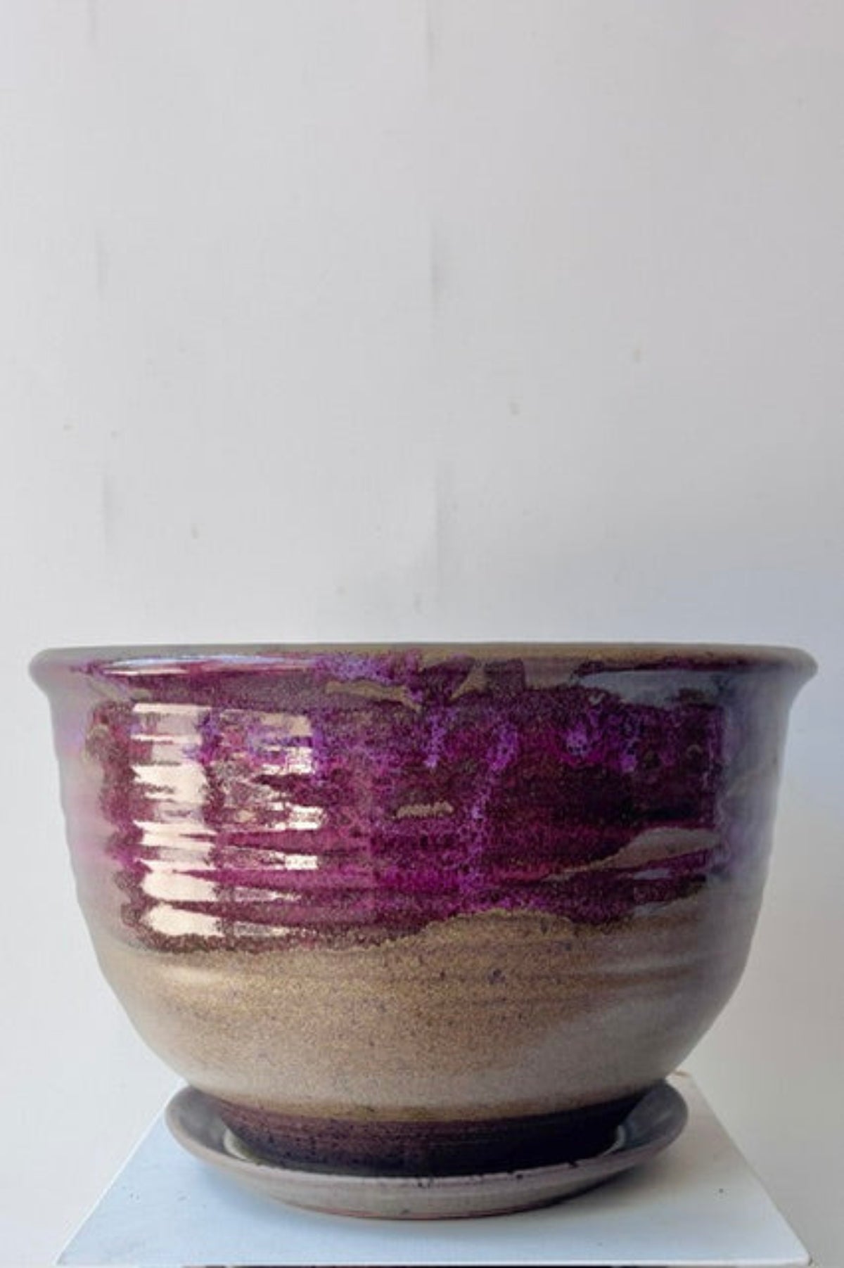 A handmade ceramic planter bowl with a glossy purple and metallic gold-brown gradient glaze, sitting on a matching saucer against a plain white background.