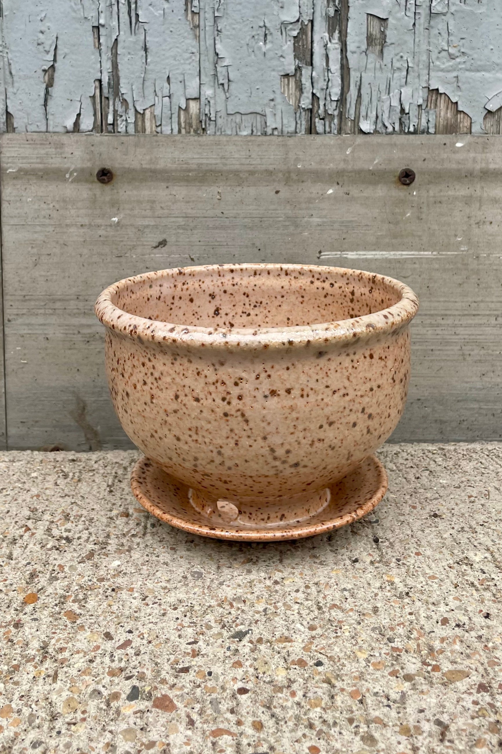 A tan speckled planter in front of a wooden wall ©Sprout Home