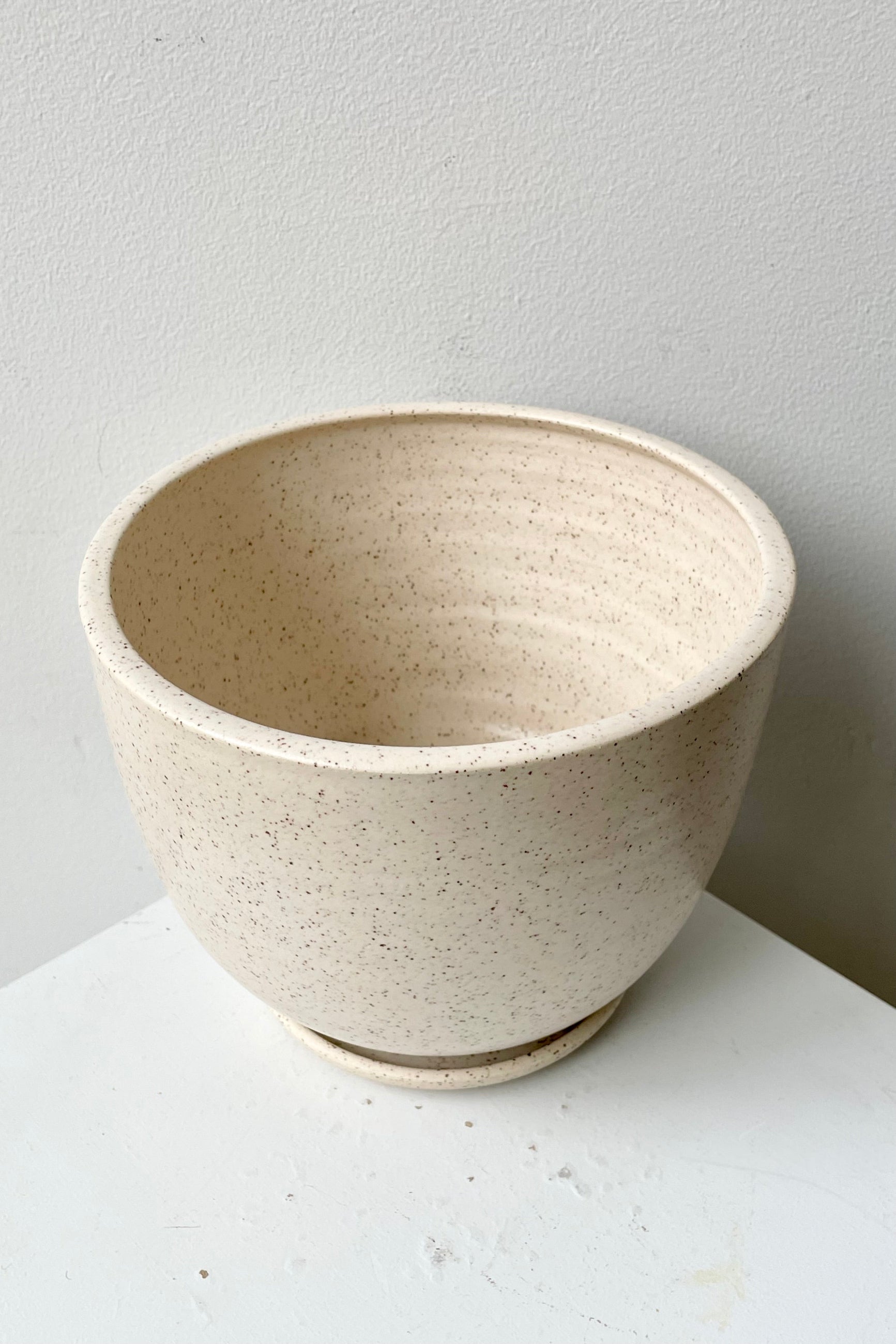 a view from above and side of the tabletop planter and saucer in the cream speckle finish.  ©Sprout Home