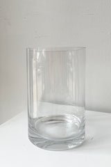A clear vase 6x4 sitting on a white pedestal looking from the side. 