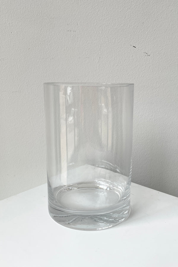 A simple clear glass vase against a white wall.
