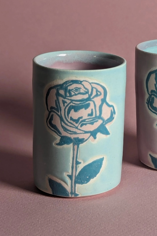 A blue ceramic shot glass with a rose pattern on the glaze ©City In Bloom Ceramics