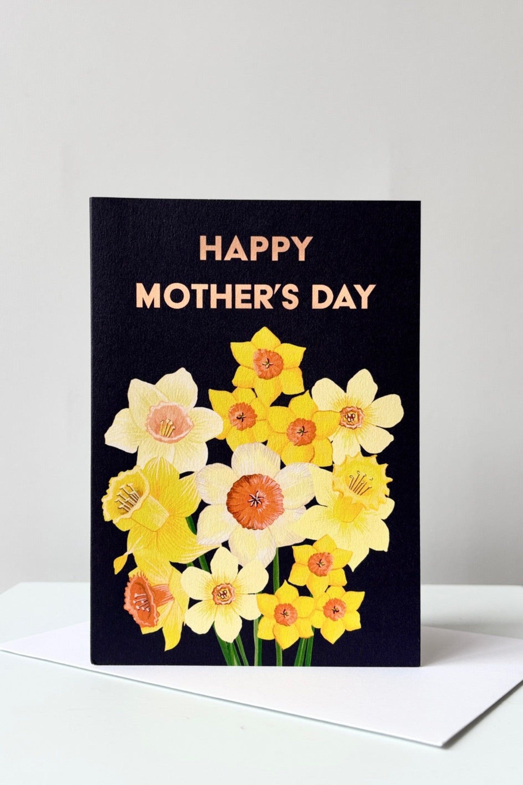 Greeting card with yellow daffodils on a black background with the words Happy Mother's Day on the front. Shown with envelope ©Sprout Home