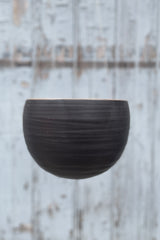 The black spherical hanging planter in matte black up close and shown from the side empty