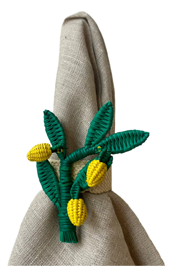 Photo of a Lemon Branch napkin ring of yellow and green palm fiber on wire. It is shown on a neutral colored napkin in front of a white background.