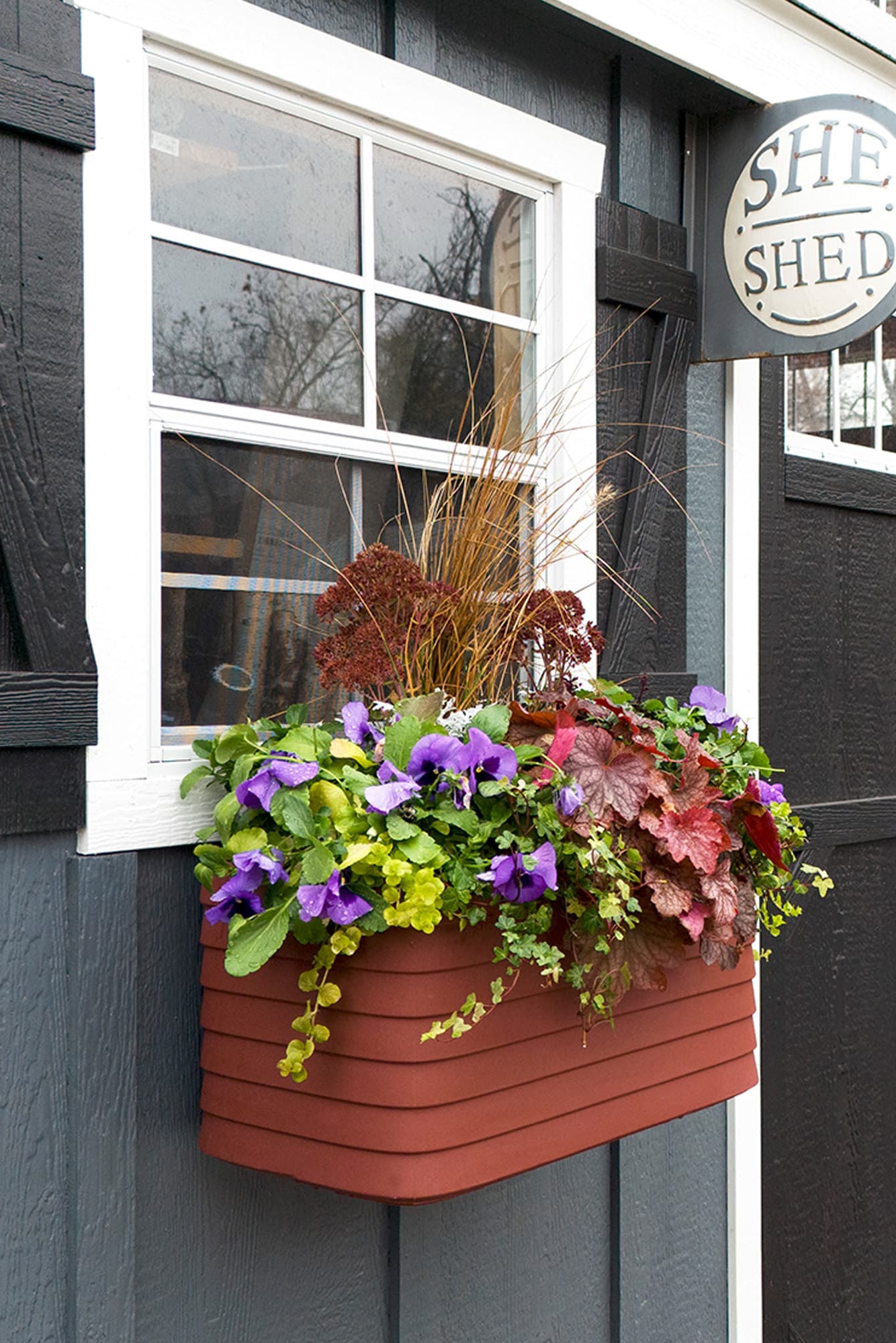 She Shed with a flower box and decorative sign on a gray building. ©Crescent