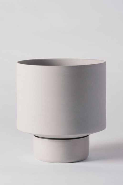 A light grey Collector's Gro pot by Angus & Celeste empty and against a white wall. 