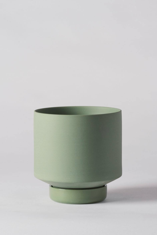 An Olive Green Collectors Gro pot by Angus & Celeste, against a white wall not potted. 