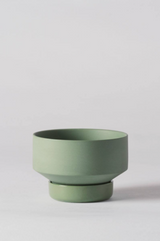 A small Olive Green Collector's Gro pot by Angus & Celeste empty and against a white wall. 