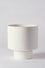 A white Collector's Gro pot by Angus & Celeste empty and against a white wall. 