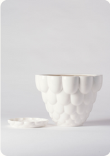 A white Jelly Planter by Angus & Celeste shown with its detachable saucer to the side of the pot. 