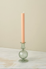 Glass Nahlia candlestick holder in Parakeet color with a peach colored taper candle. 