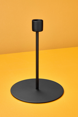 The Kent tall black metal candlestick holder against yellow