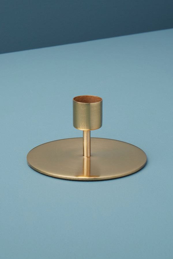 Kent Gold candlestick holder in gold against a contrasting blue background.