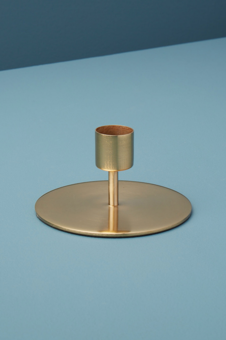 Kent Gold candlestick holder in gold against a contrasting blue background.