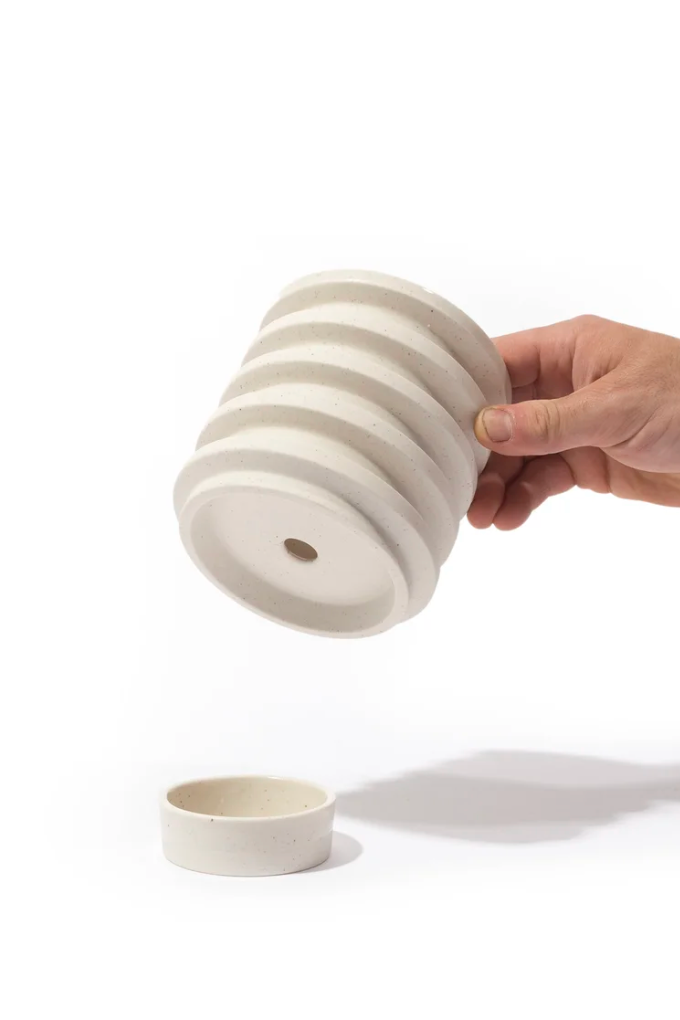 Hand holding a striped ceramic object with another similar object on a white background ©Andrew Molleur Studio