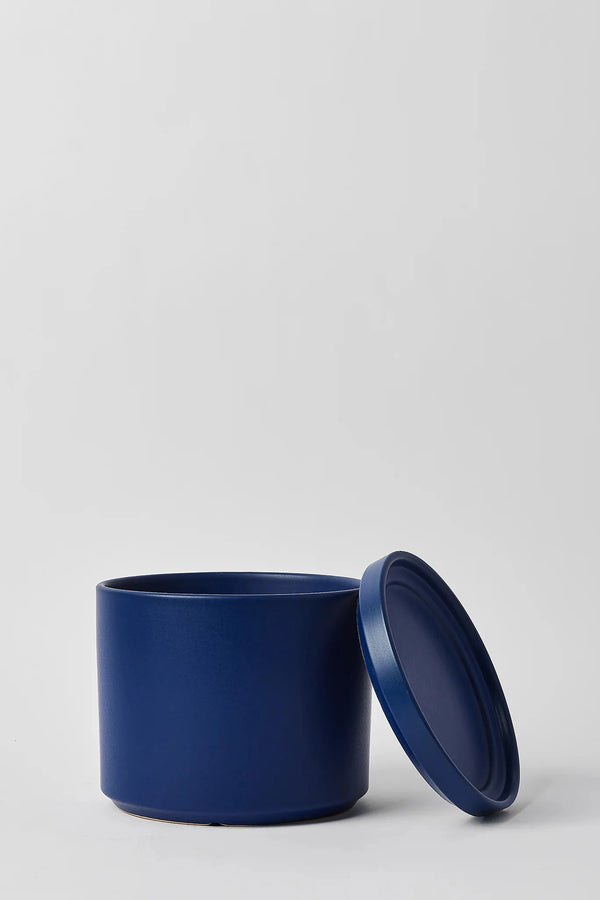 LBE Design blue solid goods cylinder and saucer with the saucer leaning against the pot.