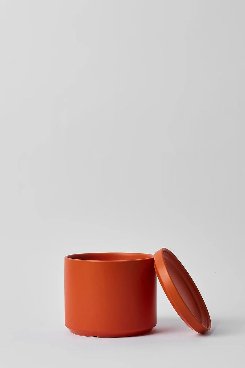 LBE Design Solid Goods cylinder and saucer in Rust with its saucer laying against the pot. 