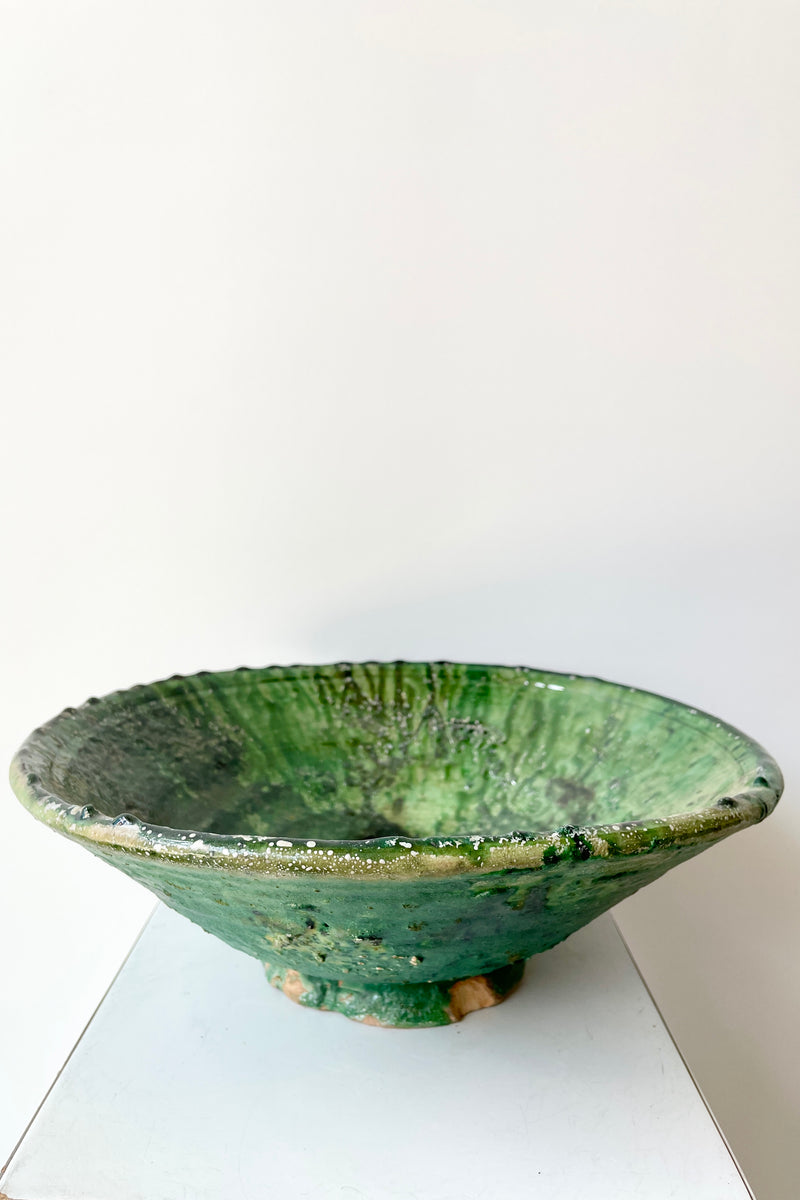 The large tamaegroute green bowl at Sprout Home shown from the side against a white wall. 