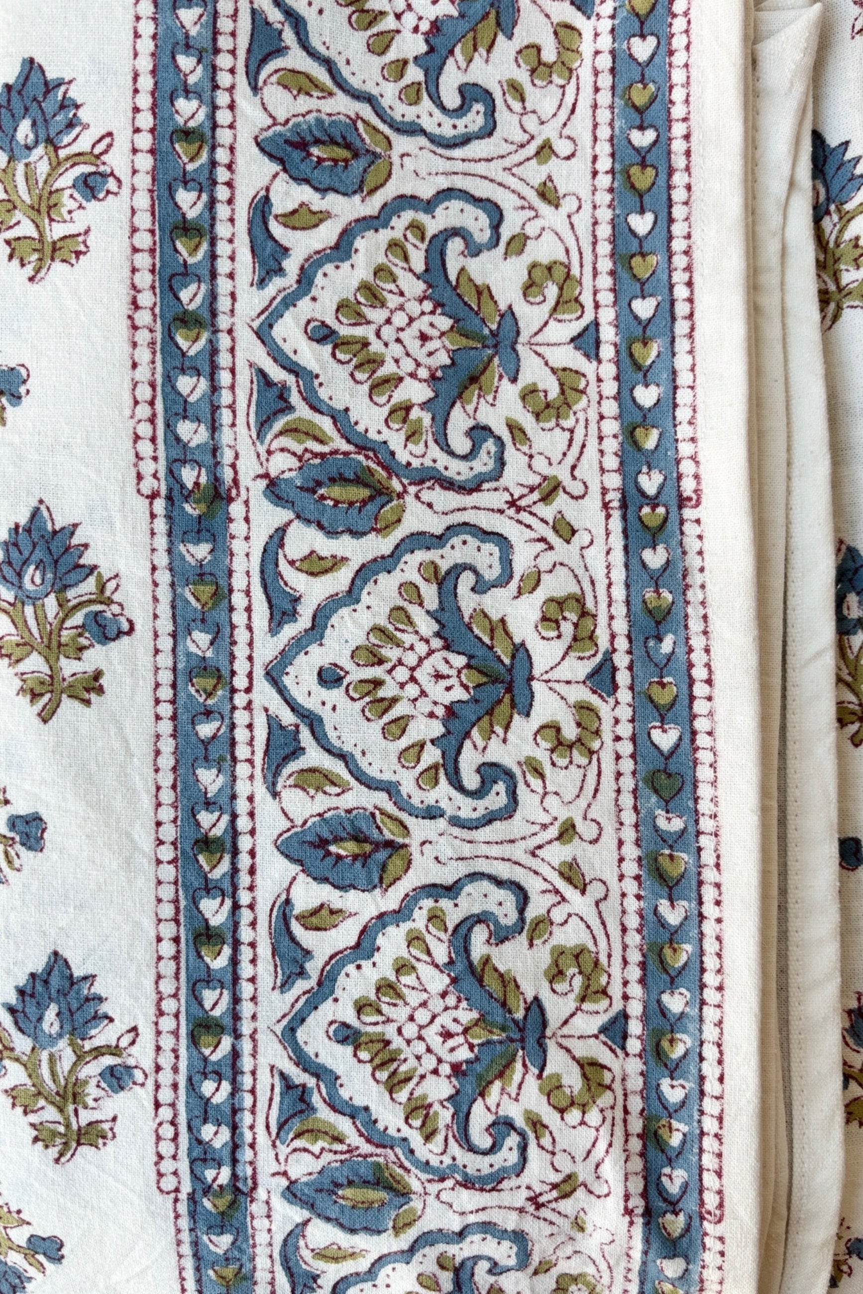 Trim detail of hand printed Silvia tablecloth with blue and green filagree floral design on a white background ©Sprout Home