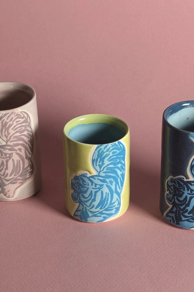 Ceramic cups in Chartreuse with a tiger patterns on a pink background ©City in Bloom Ceramics