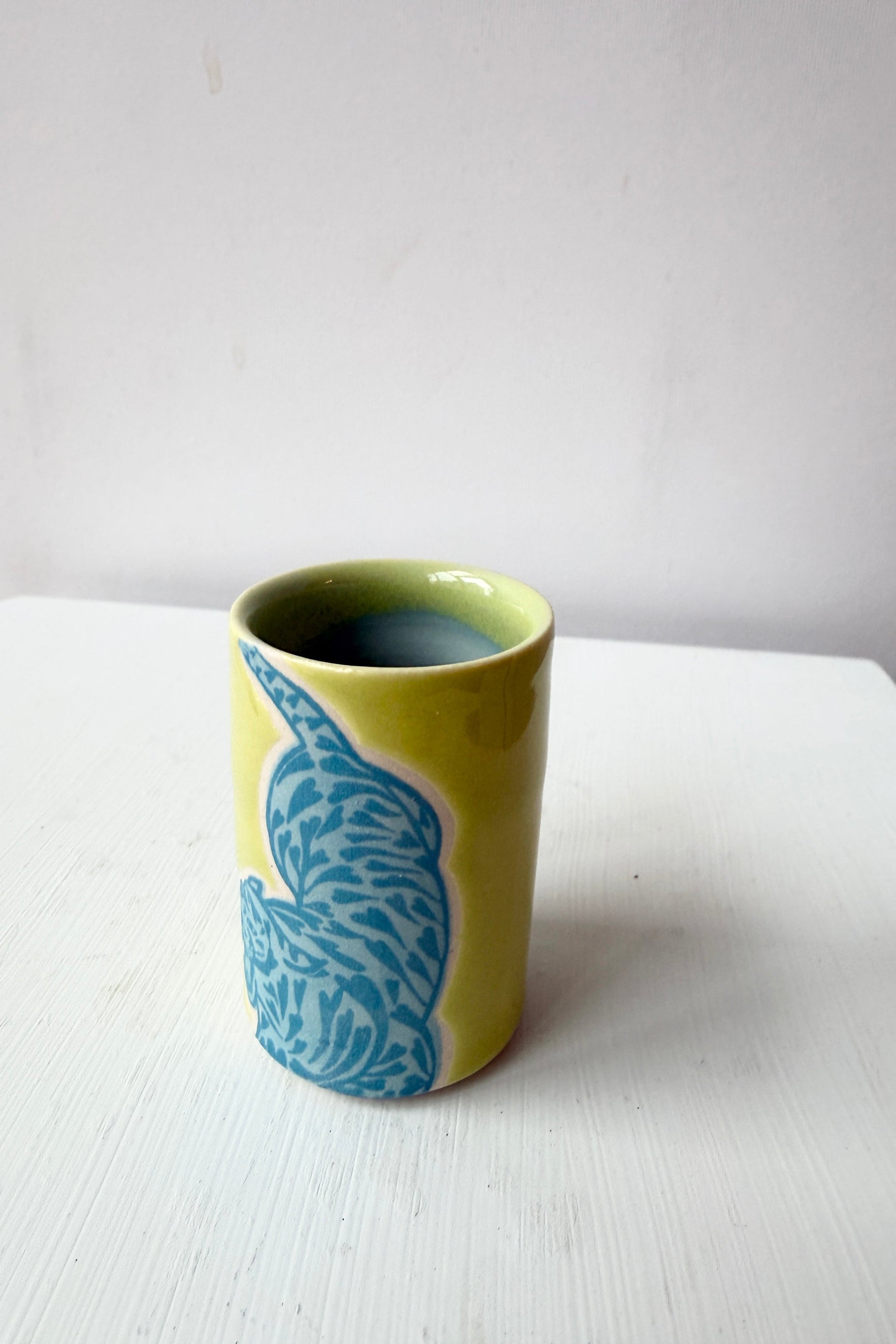 Green ceramic cup with blue tiger pattern  by City in Bloom Ceramics on a white surface ©Sprout Home