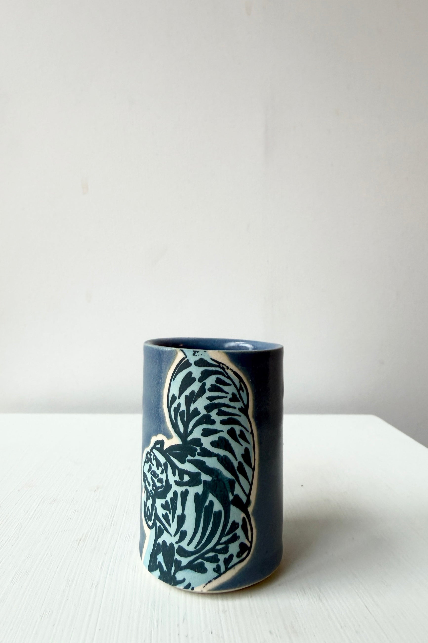 Ceramic tumbler with blue and white tiger by City in Bloom Ceramics on a white surface ©Sprout Home