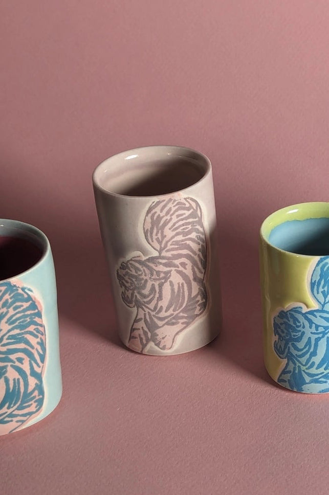 Ceramic cups with animal patterns on a pink background focusing on the mauve colored one in the center ©City in Bloom Ceramics